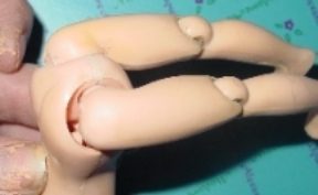 Close-up of a jointed doll's arm with visible joints and a mouth.