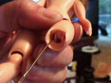 Close-up of a hand holding a small doll with a hole in its torso.