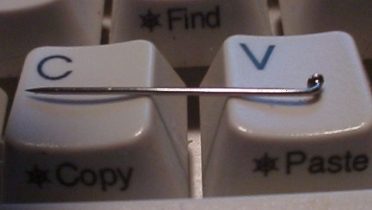 A sewing needle resting on computer keyboard keys.